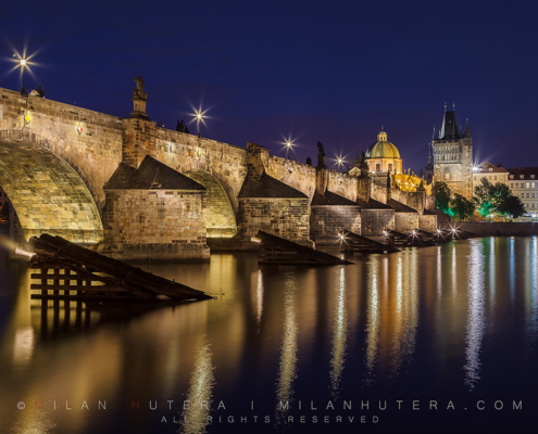 Quiet summer twilight at Charles' Bridge in Prague. The dome of the Church of Francis of Assisi and Old Town Bridge Tower are visible in the back.