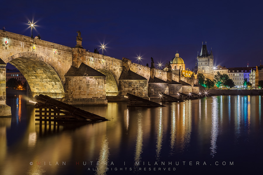Quiet summer twilight at Charles' Bridge in Prague. The dome of the Church of Francis of Assisi and Old Town Bridge Tower are visible in the back.