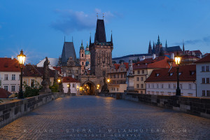 A warm summer dawn near Charles' Bridge Towers on Malá Strana. The Prague Castle with St. Vithus Cathedral is visible in the distance.