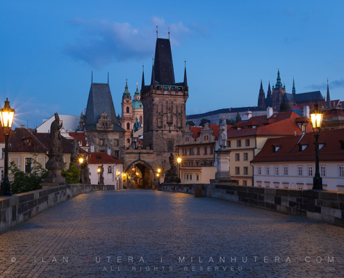 A warm summer dawn near Charles' Bridge Towers on Malá Strana. The Prague Castle with St. Vithus Cathedral is visible in the distance.