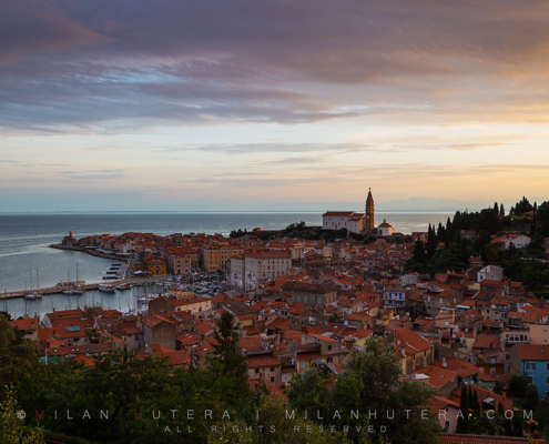 Subtle clouds with purple and yellow hues above the port city of Piran, Slovenia.