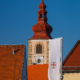 The tower of Church of Saint George and the flag with coat of arms of Ptuj in an afternoon light.