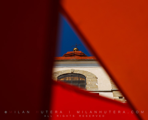 The tower of the Church of Saint George in Ptuj, Slovenia, framed by the sunshades of nearby caffe.