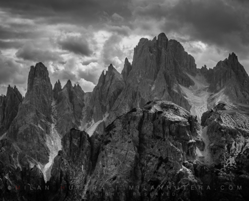 A dramatic black and white rendition of a cloudy early afternoon light at Cadini di Misurina. The sharp jagged peaks are located in the vicinity of Tre Cime di Lavaredo mountain range.