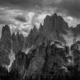 A dramatic black and white rendition of a cloudy early afternoon light at Cadini di Misurina. The sharp jagged peaks are located in the vicinity of Tre Cime di Lavaredo mountain range.