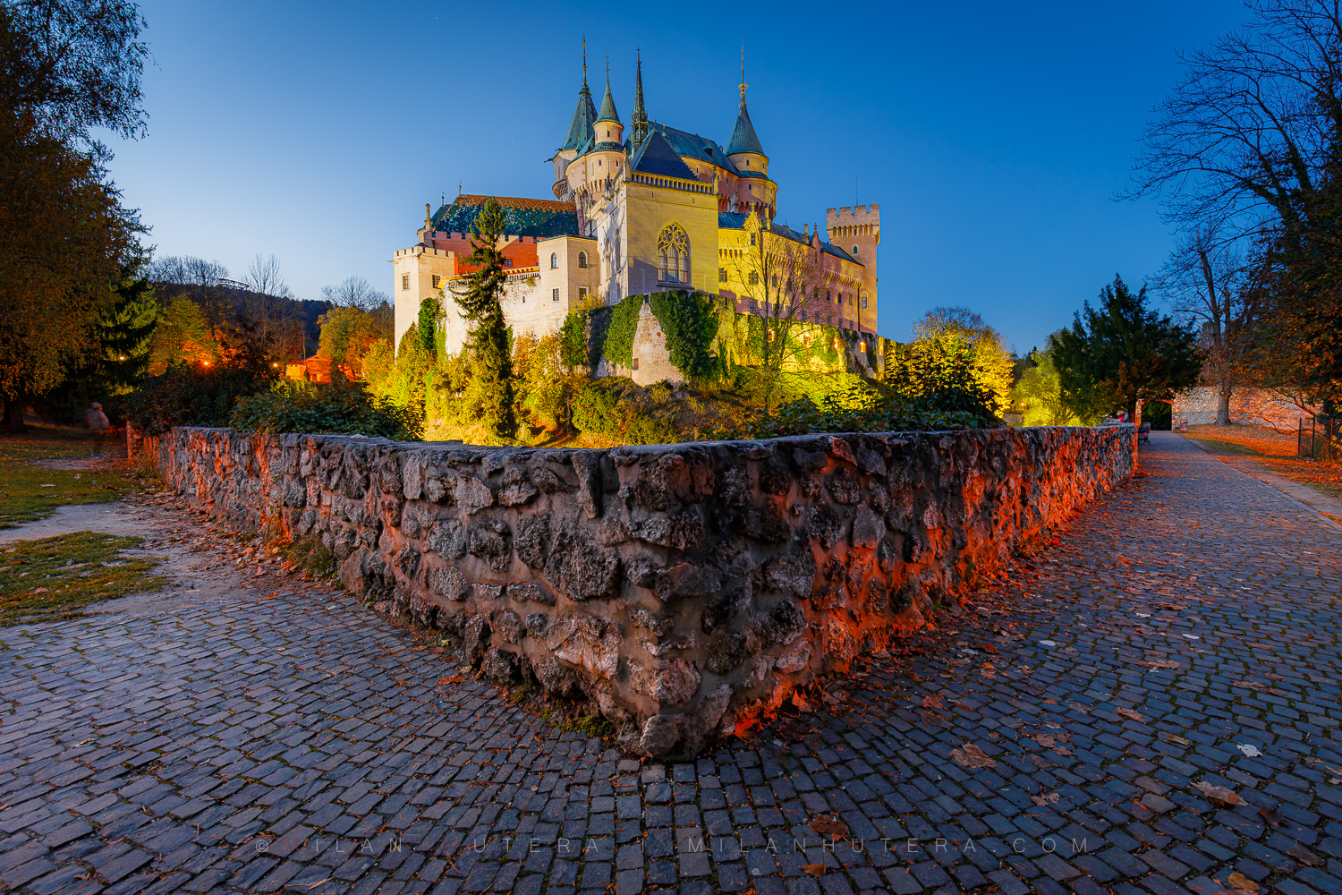 Late autumn evening at Bojnice Castle with old warm amber lighting and autumn trees