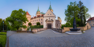 A wide-angle perspective of the castle entrance, bathed in the soft glow of the evening Sun."