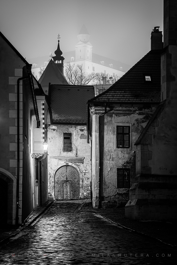 Black and white photography of Farská Street in Bratislava, with the Castle in the fog.