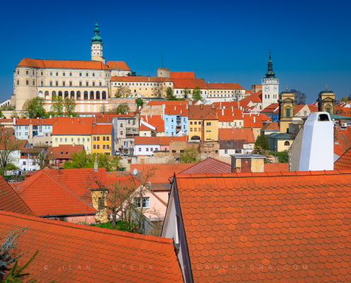 View of red rooftops in Mikulov, Czech Republic, with Mikulov Castle under a clear blue sky, shot from the steps to Svatý kopeček