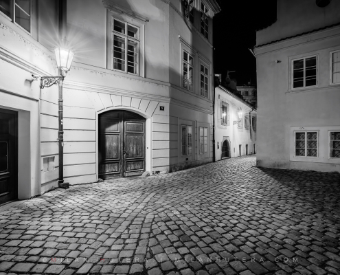 Black and white night photograph from the series Ve Stinadlech showing an old dark Prague alley as featured in Rychlé Šípy novels and comics by Jaroslav Foglar