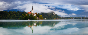Panoramic view of Bled Lake in Slovenia on a foggy morning with the island church, Bled Castle and the town of Bled reflected in the Bled Lake
