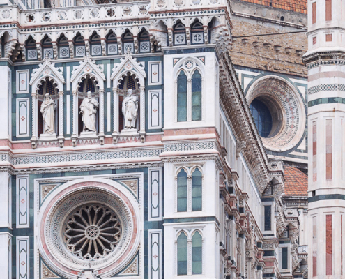 Close-up of Florence cathedral facade details with pink green and white marble panels under an overcast sky