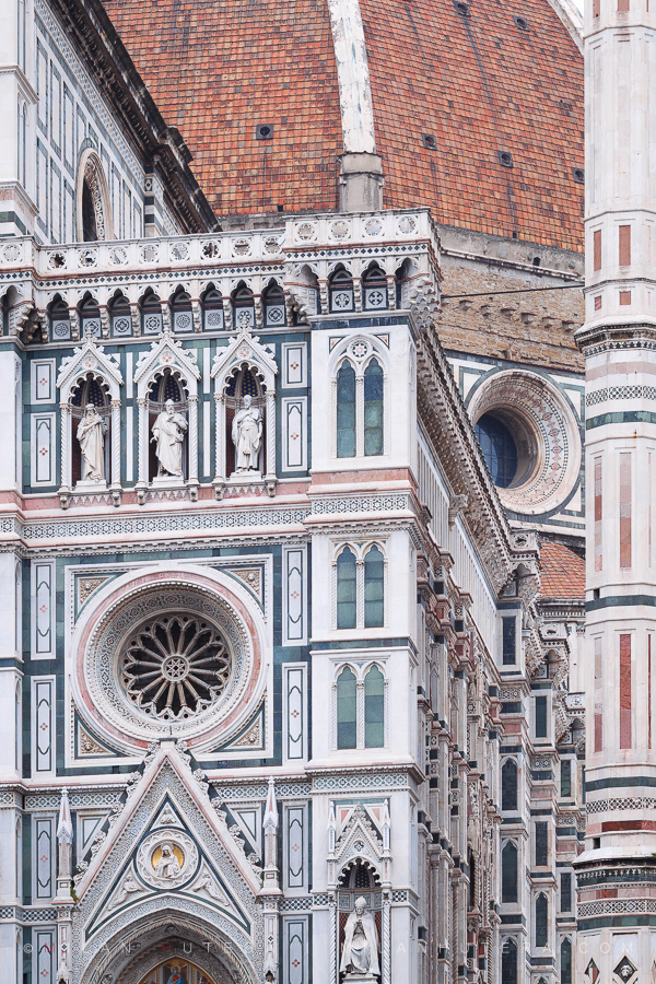 Close-up of Florence cathedral facade details with pink green and white marble panels under an overcast sky