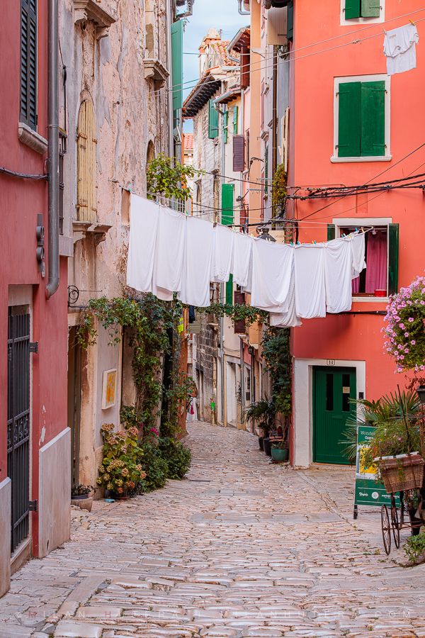 Rovinj narrow streets with colorful houses and white laundry drying between historic stone buildings