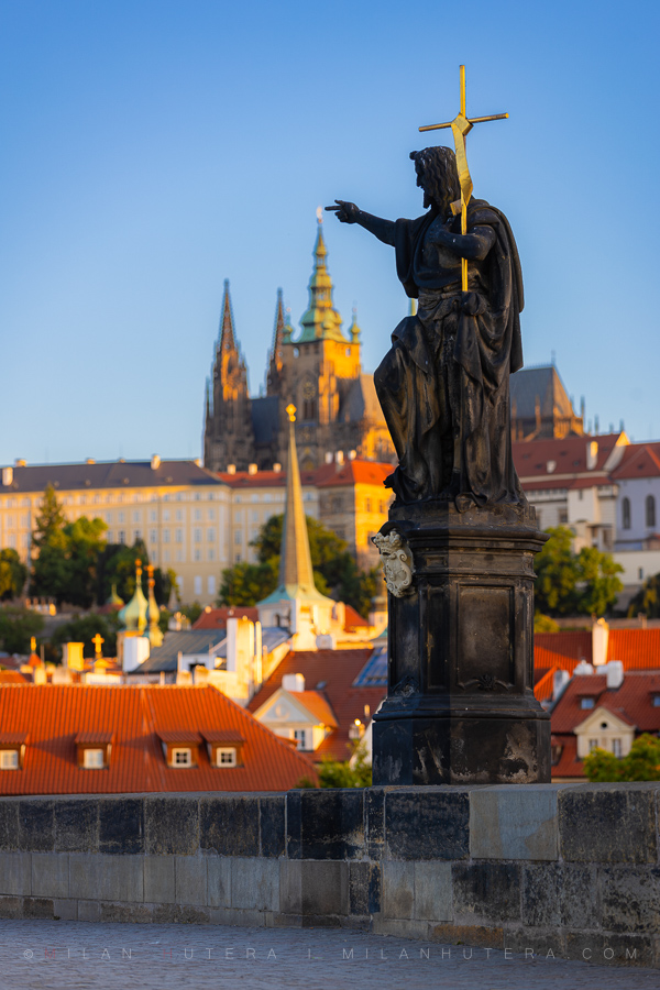 The Saint's Touch, Prague, Czech Republic The Saint's Touch, Prague, Czech Republic — St John the Baptist statue on Charles Bridge "touches" the distant spire of St Vitus Cathedral in the morning light