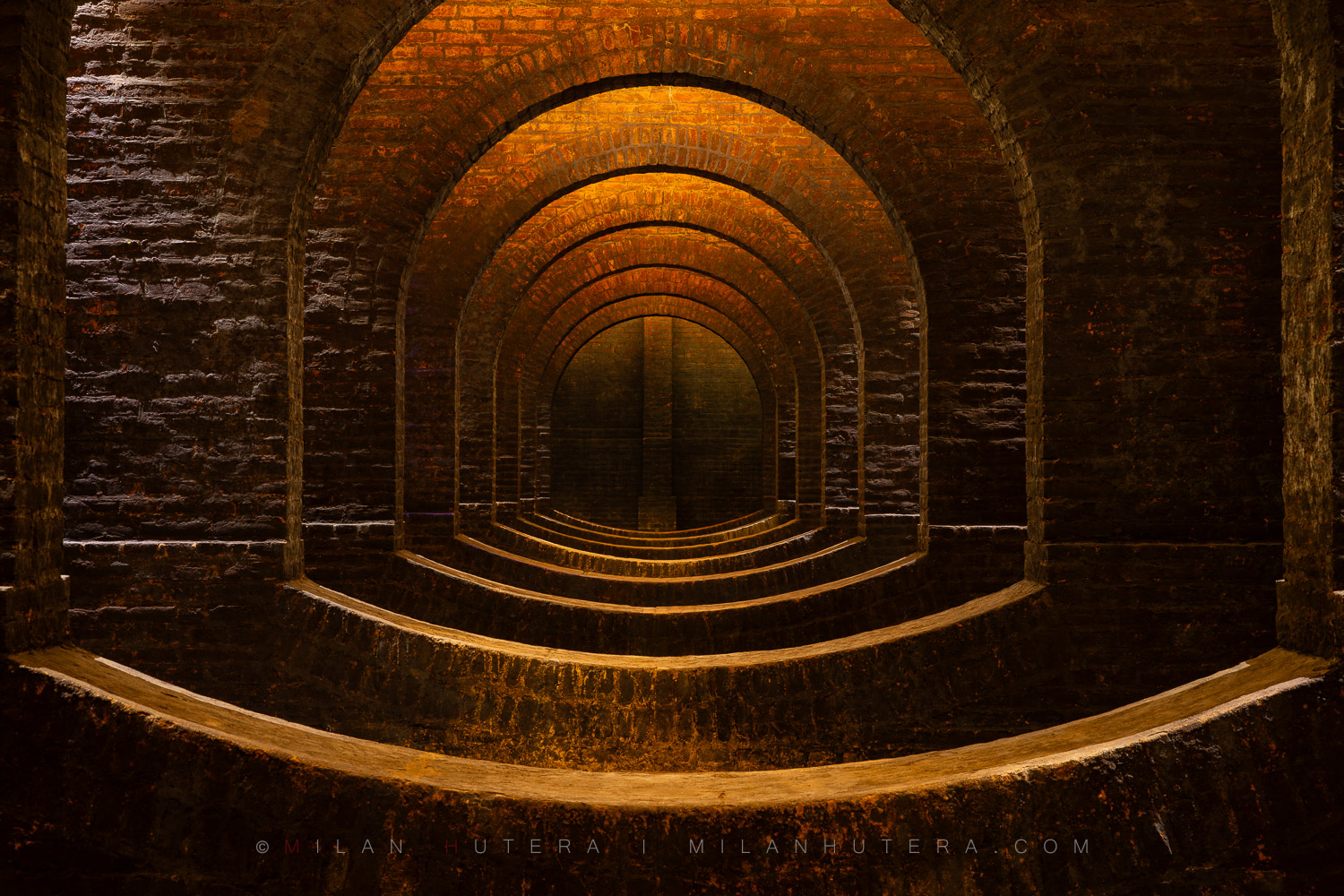 Vodojemy Žlutý Kopec - 1874, Brno, Czech Republic A geometric perspective looking centrally through a row of brick arches and inverted barrel vaults inside the 1874 Žlutý kopec water reservoir.