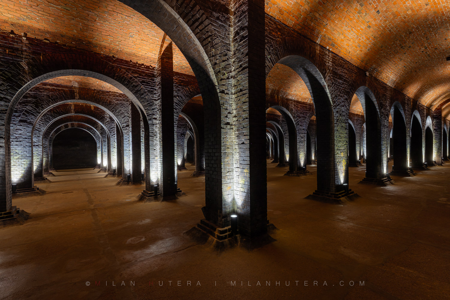 1894 Žlutý Kopec Water Reservoir, Brno, Czech Republic An asymmetrical, wide-angle interior photograph of the 1894 Žlutý Kopec water reservoir in Brno, showcasing a vast forest of brick pillars and cross-vaulted ceilings.