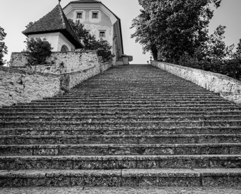 Bled Lake island stairs leading up to the historic church, captured in black and white, looking up from the bottom of the 99 steps.