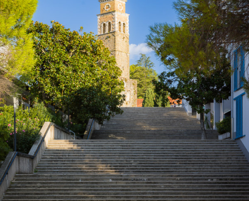 A photo of the St. Bernardin Tower in Portorož, Slovenia, showing the stone stairs leading up to the historic church ruins.