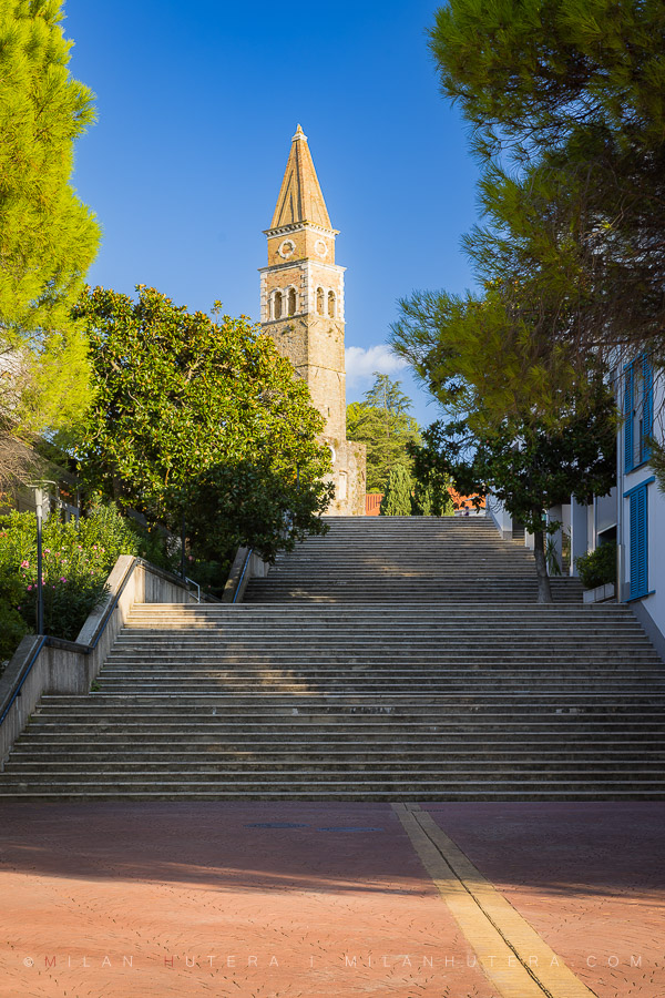 A photo of the St. Bernardin Tower in Portorož, Slovenia, showing the stone stairs leading up to the historic church ruins.