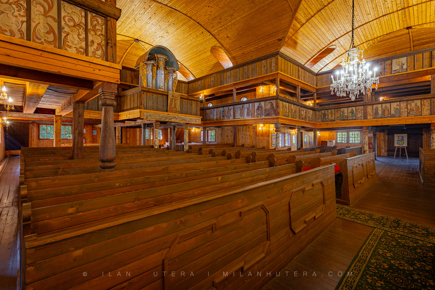 Interior of the Svaty Kriz Wooden Church in Liptov, Slovakia featuring historic pews and painted galleries.