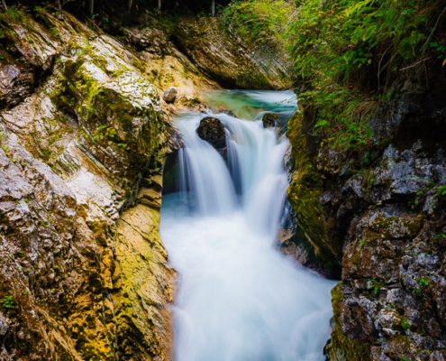 Vintgar Gorge Rapids with a wooden tourist walkway and a turquoise waterfall in Bled, Slovenia