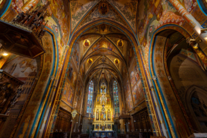 The magnificent Vysehrad Basilica sanctuary in Prague showcasing the golden high altar and stained glass windows.