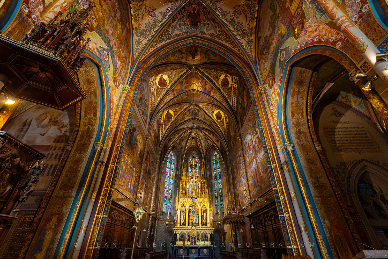 The magnificent Vysehrad Basilica sanctuary in Prague showcasing the golden high altar and stained glass windows.