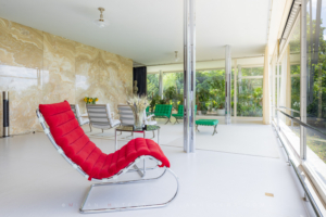 Villa Tugendhat living room featuring red chaise longue, Barcelona chairs, and translucent onyx wall