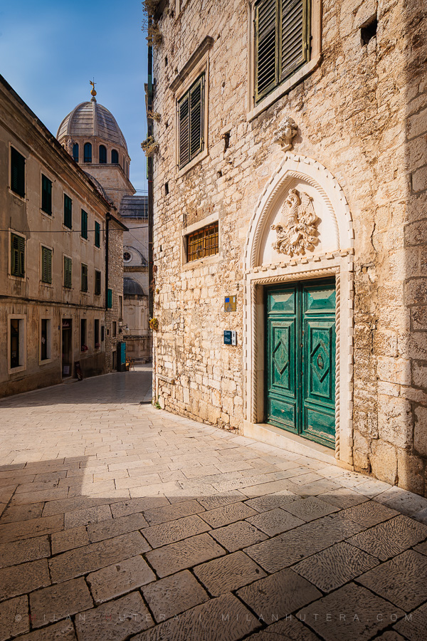 Empty Šibenik old town street with a Gothic portal and the dome of St. James Cathedral in the background