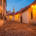 Kapitulská Street in Bratislava at blue hour with warm street lamps, historic façades and the Clarissine Church tower in the distance